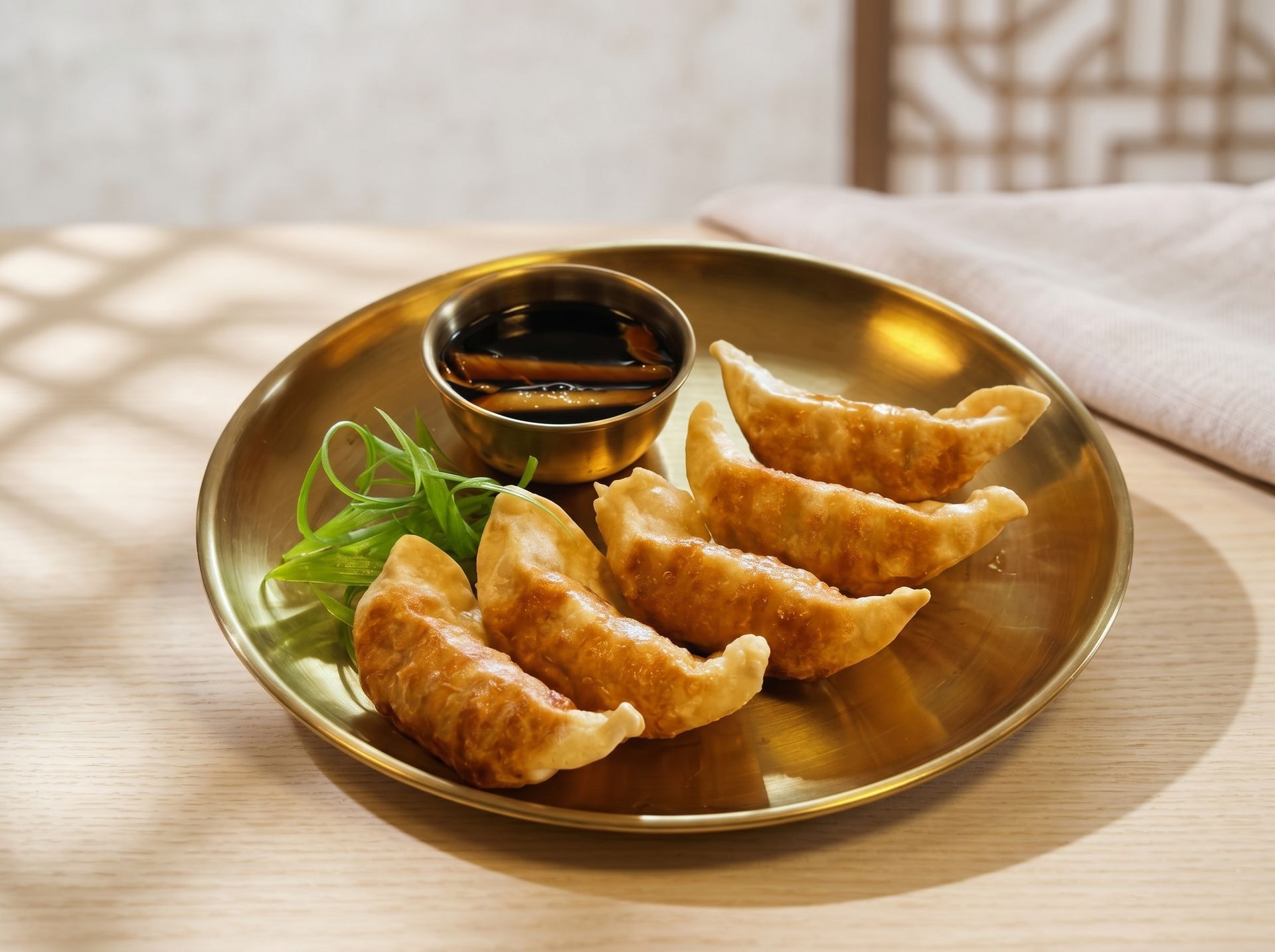 Golden plate of fried dumplings with dipping sauce and greens on a wooden table