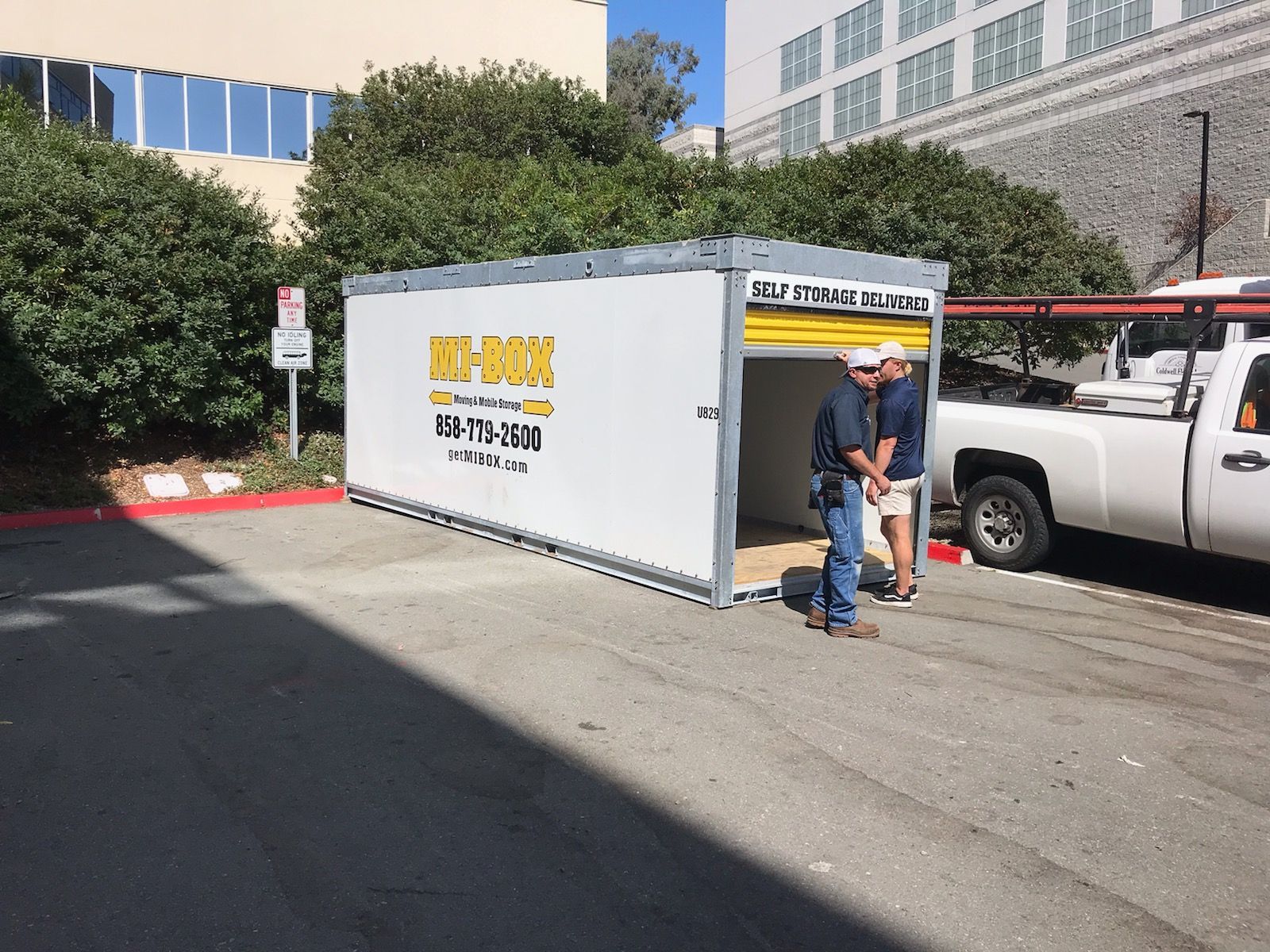 Two men are standing in front of a container that says key box