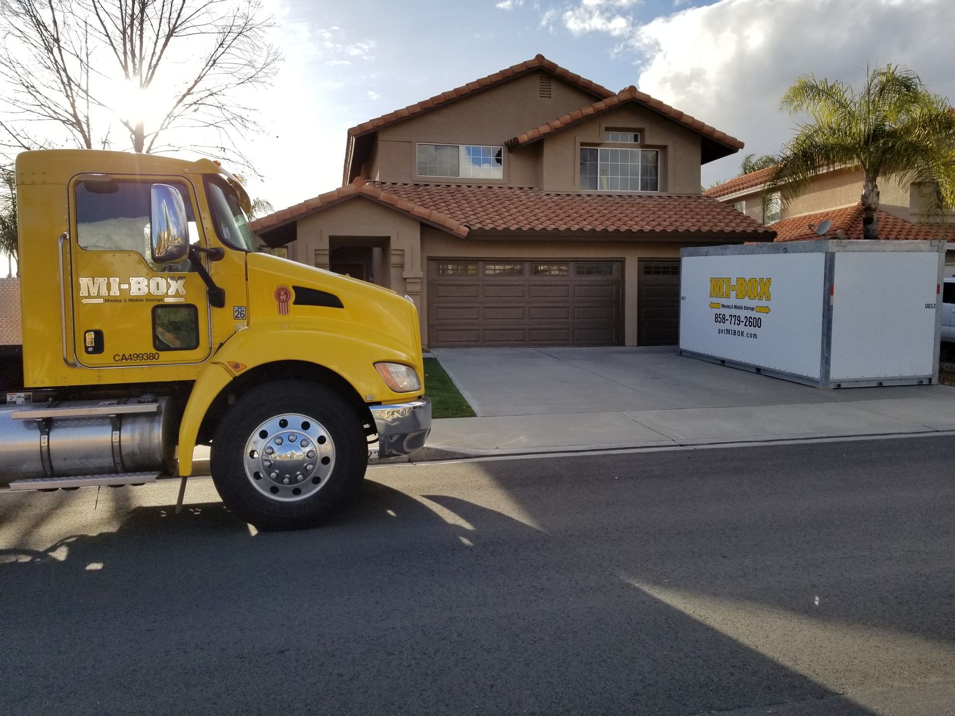 A yellow box truck is parked in front of a house