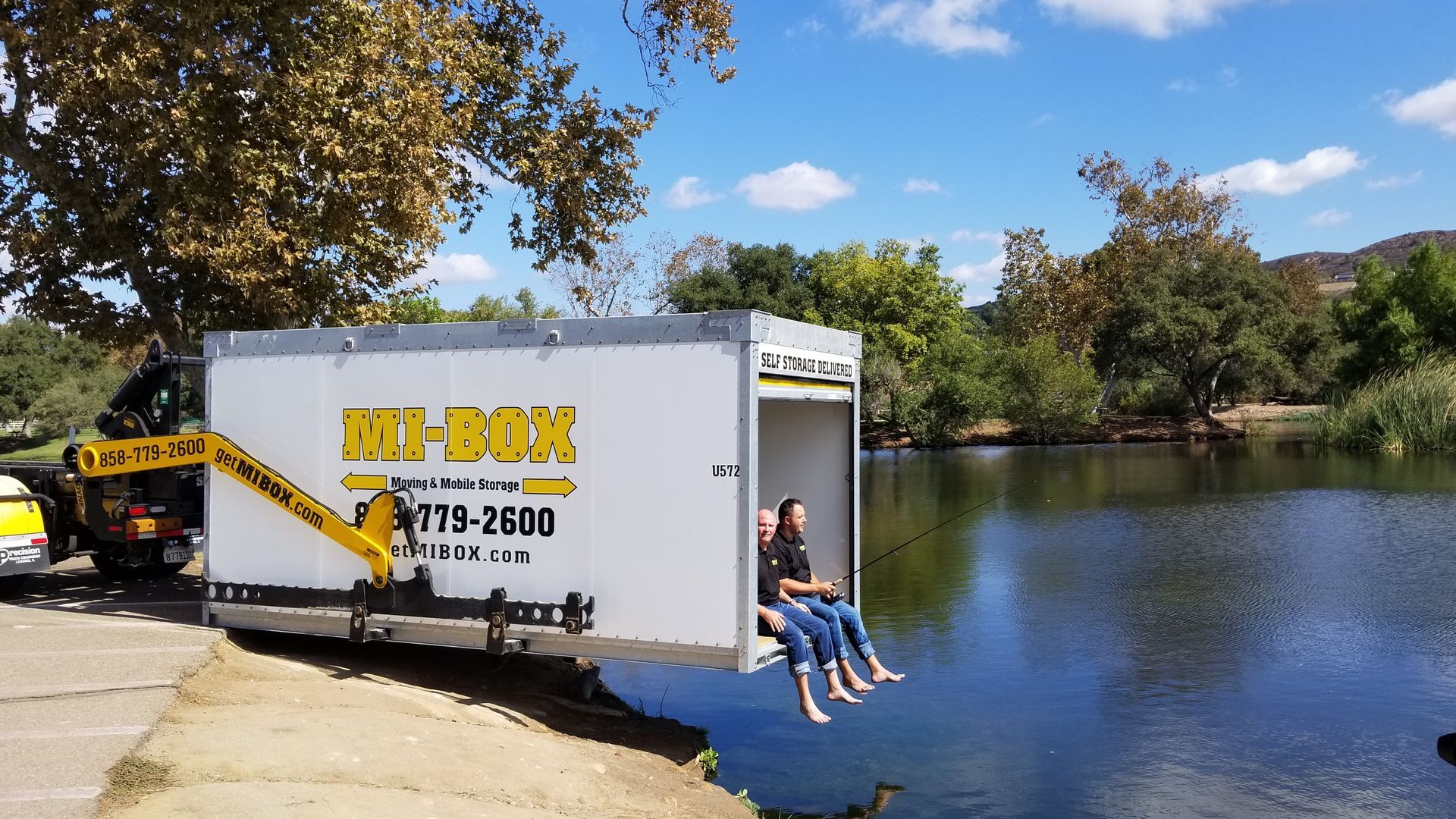 Two people are sitting in the back of a mi-box truck