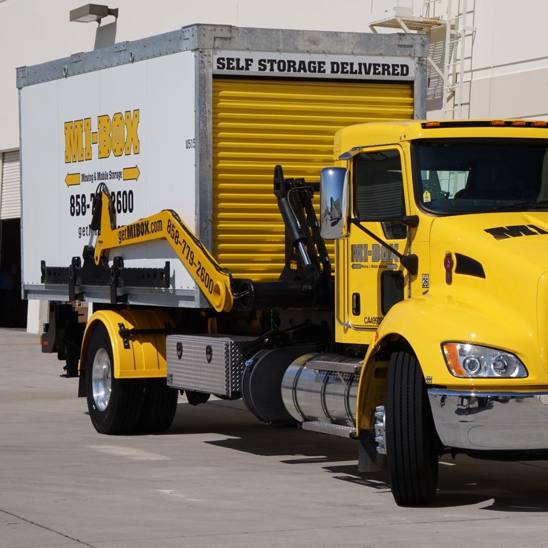 A yellow truck is pulling a white box that says self storage delivered