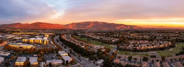 An aerial view of a city at sunset with mountains in the background.