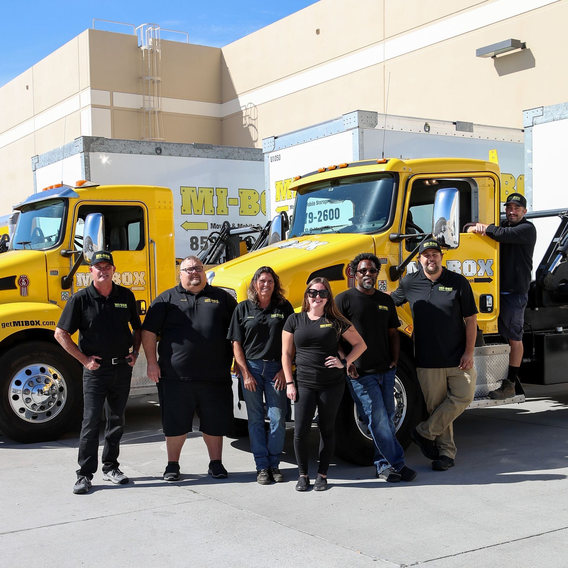 A MI BOX San Diego team standing in front of a yellow truck that says mb