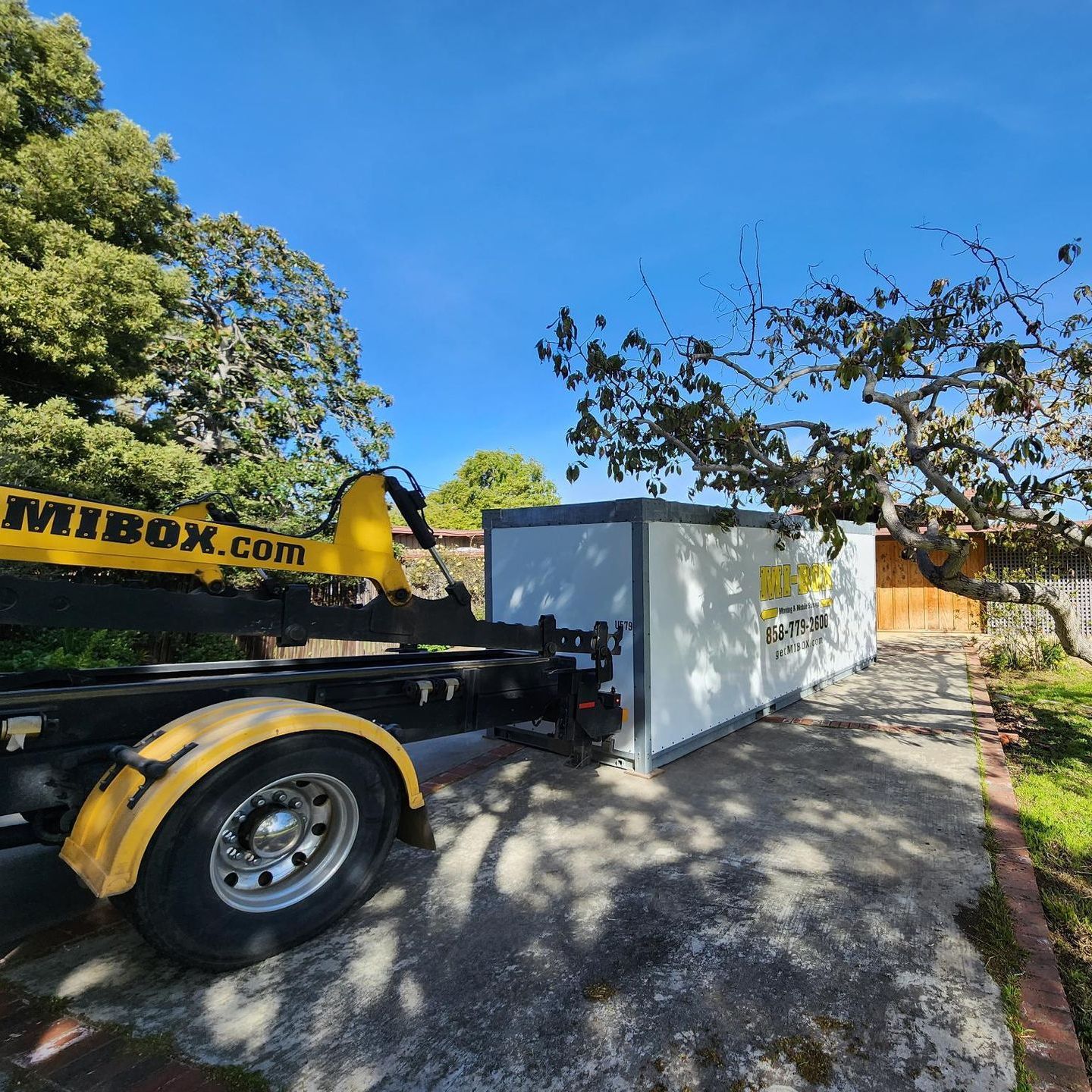 A yellow and black dump truck is parked next to a white container.