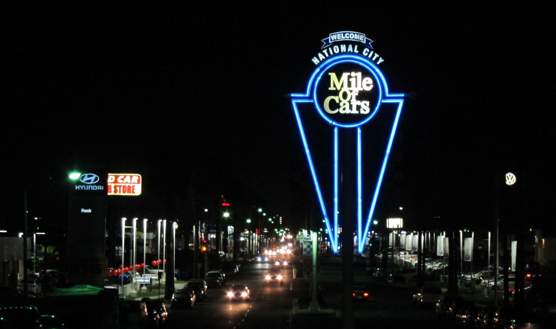 A neon sign for mile of cars is lit up at night