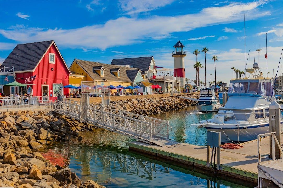 A marina with boats docked and a lighthouse in the background.