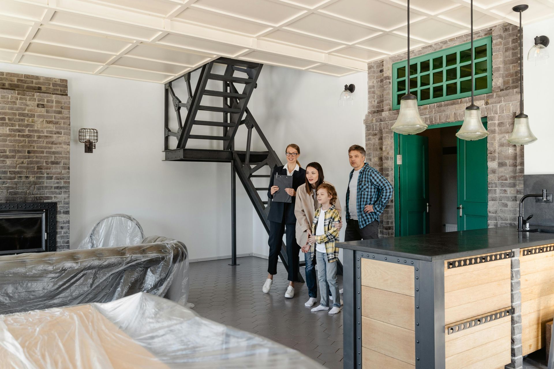 Family standing in a bright living room with a black staircase and green fireplace accents