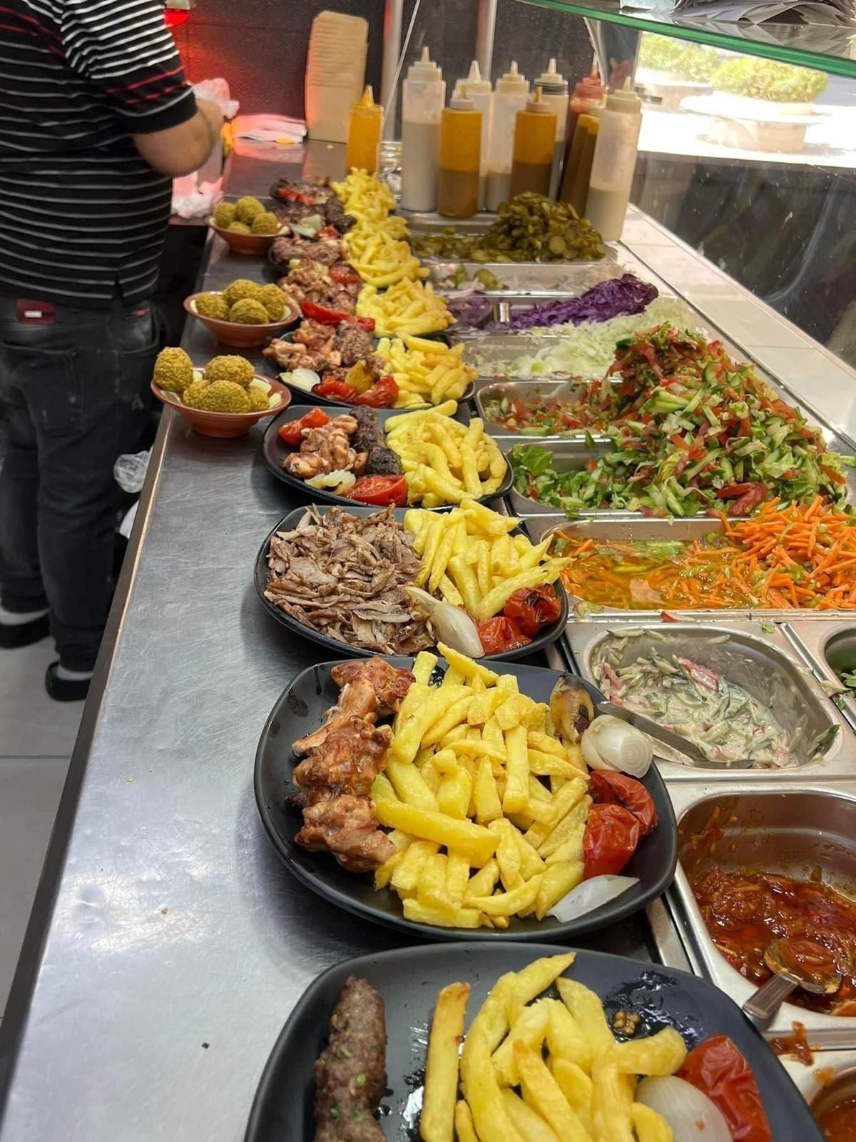 שולחן בופה עם סלטים מגוונים, תפוחי אדמה מטוגנים ומנות צלויות במגשים ובקערות