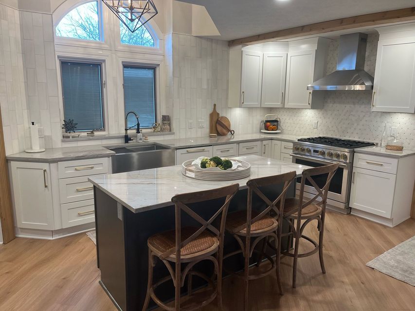 a kitchen with white cabinets , stainless steel appliances , and a large island .