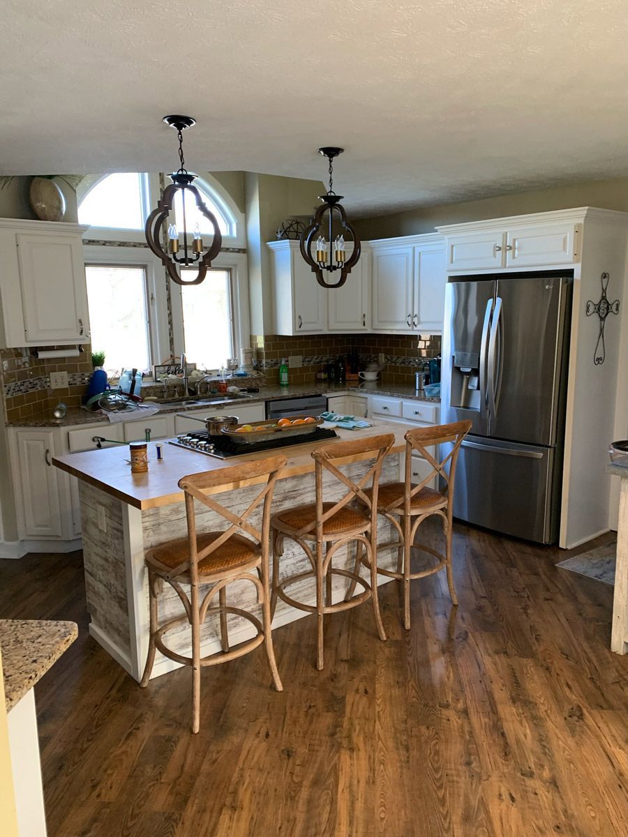 a kitchen with a large island , stools , a refrigerator and a sink .