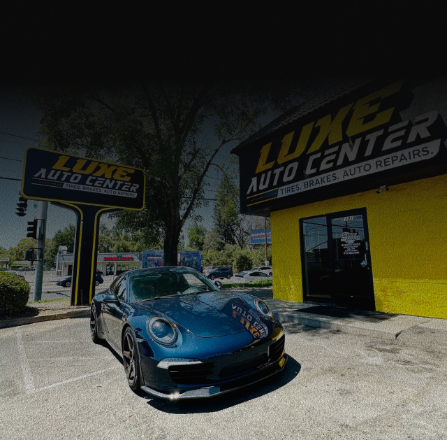 Blue car parked outside LUXE AUTO CENTER in front of a yellow garage