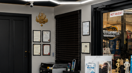 Empty office lobby with desks, computers, and black waiting chairs by a glass entrance door.