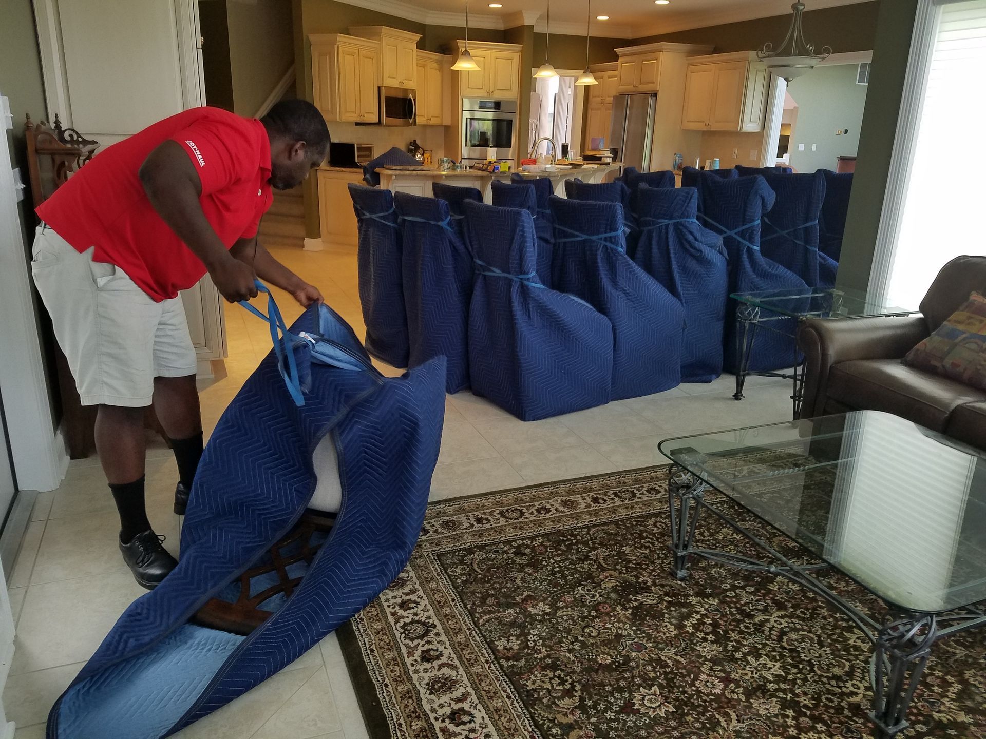 a man in a red shirt is holding a blue bag in a living room .