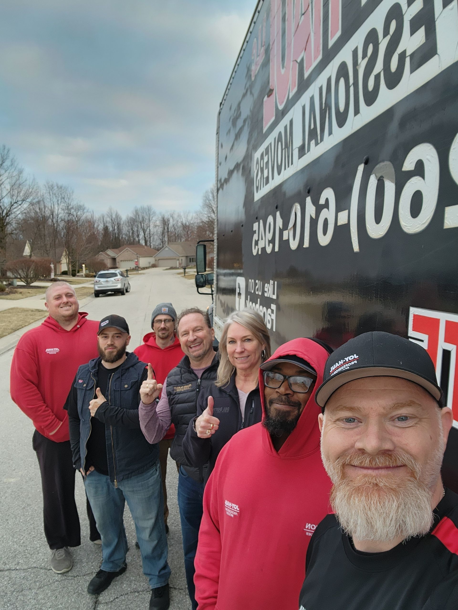 a group of people are posing for a picture in front of a moving truck .
