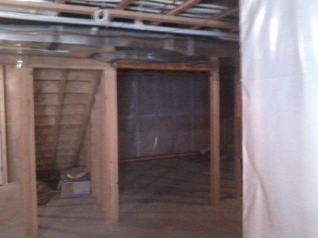 Basement interior with two unfinished doorways and exposed ceiling beams.