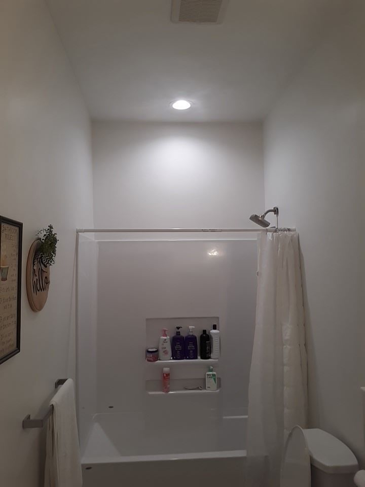 Bathroom with white walls, shower stall, toilet, and a recessed ceiling light.
