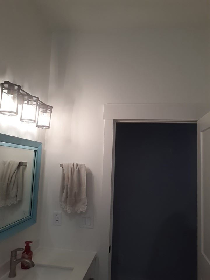 Bathroom with white walls, blue-framed mirror, and a partially open blue-painted door.