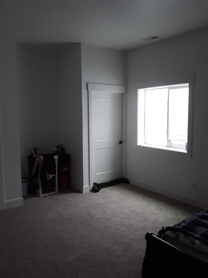 Empty room with door, window, and furniture. Gray carpet and white walls, door, and trim.
