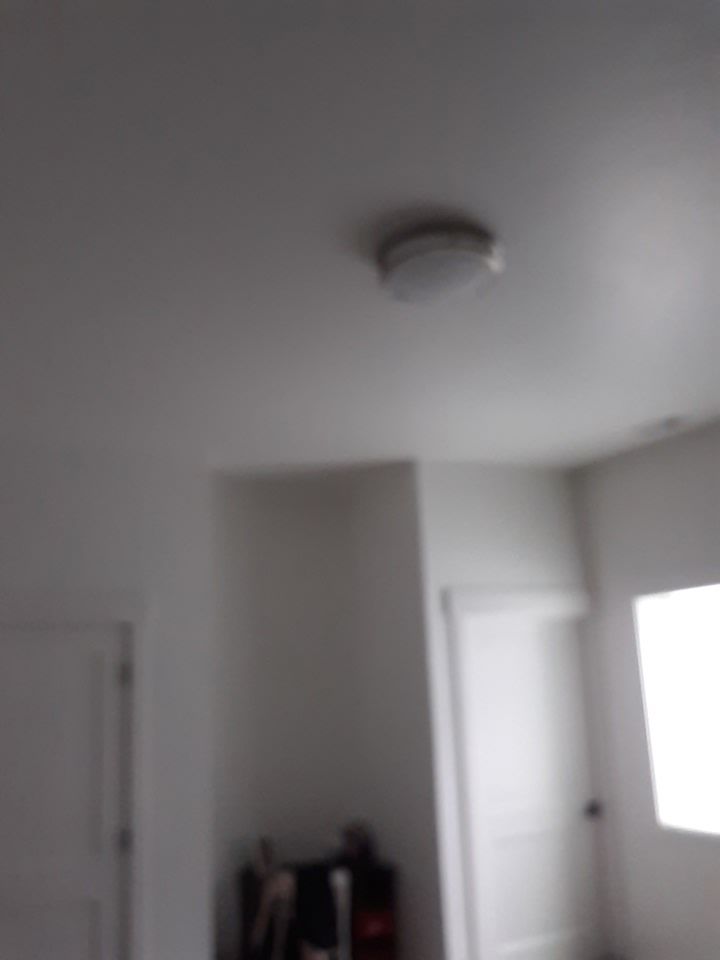 White ceiling with a circular light fixture. White walls, a doorway, and a window.