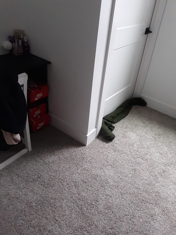 Corner of a room with a black table, white door, and green fabric on the carpet.