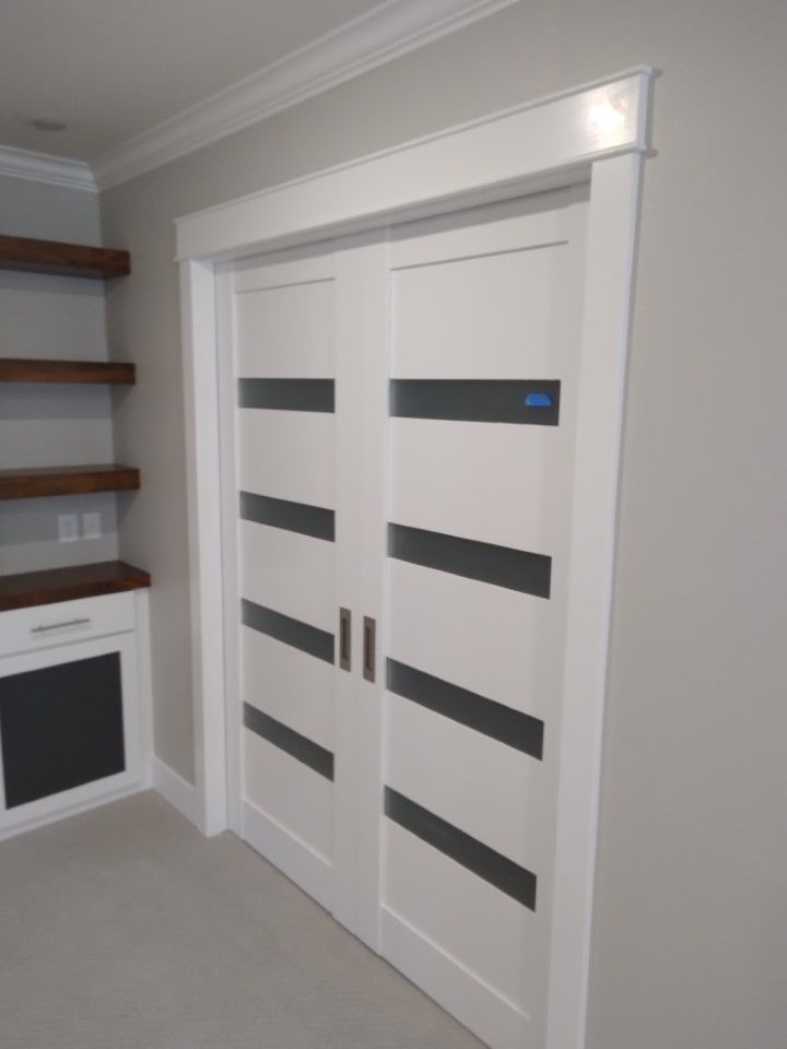 White double doors with black horizontal accents, set in white doorframe in a room.