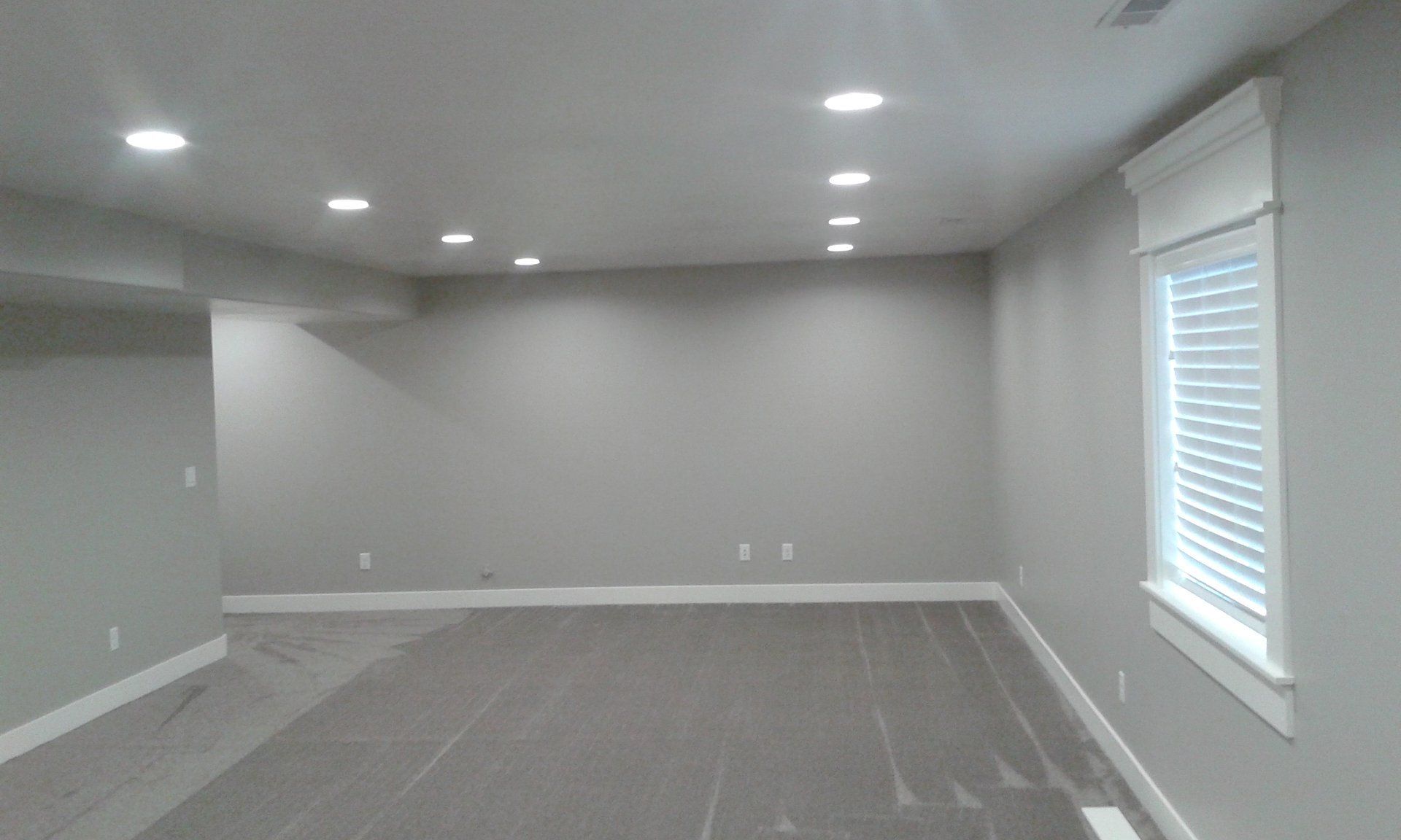 Empty room with recessed lighting, gray walls, carpet, and a window with blinds.