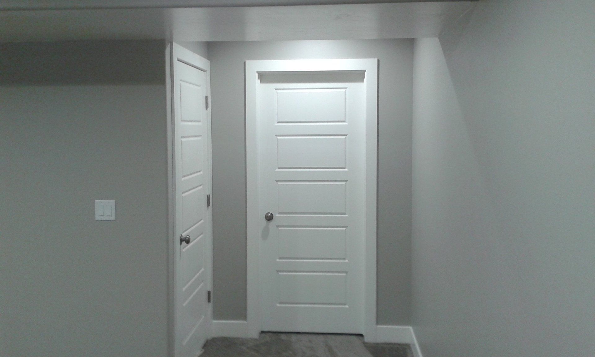Two white doors in a gray-painted room with white trim, one open and one closed.