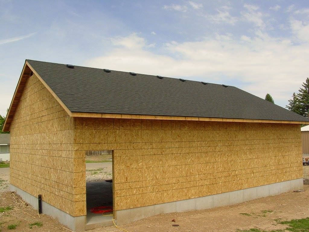 Garage under construction with OSB siding and a black shingle roof.