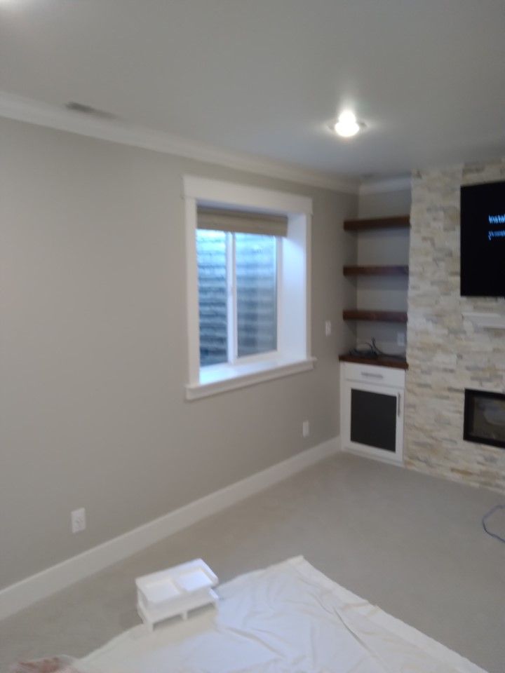 Beige-walled room with a window, shelves, and fireplace, with a white window frame and trim.