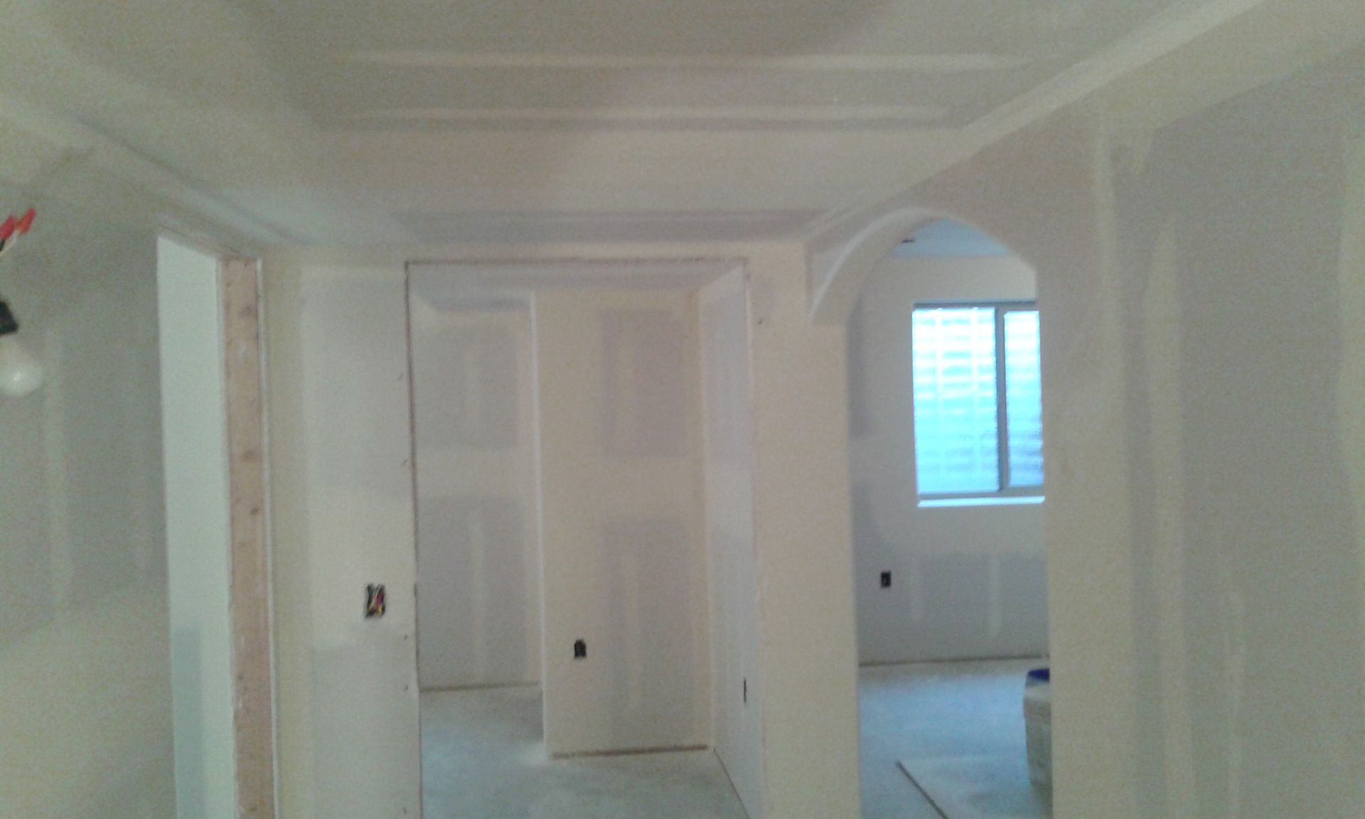 Interior hallway under construction with drywall and arched doorway.