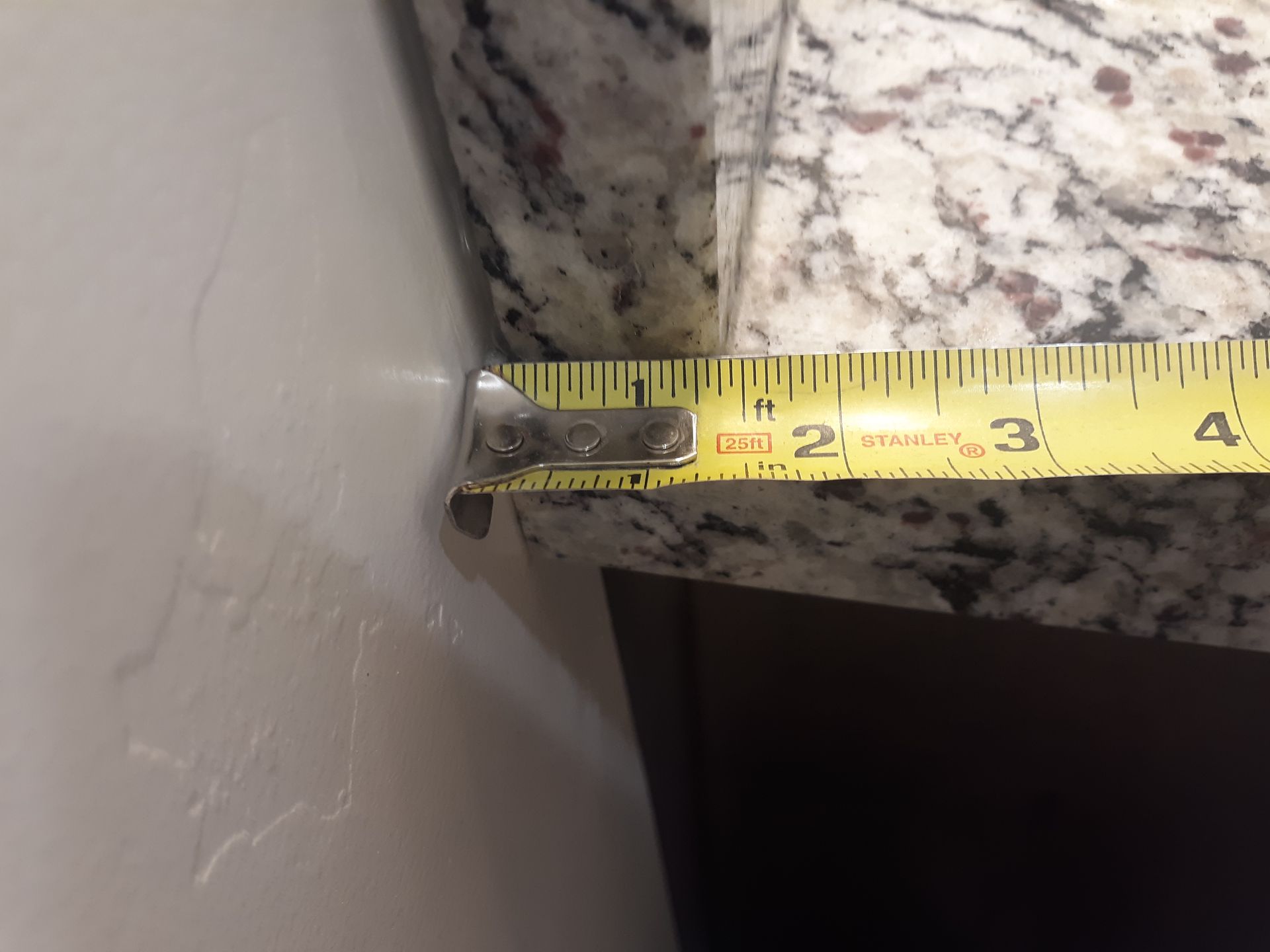 A measuring tape shows a countertop edge is about 2 inches thick.