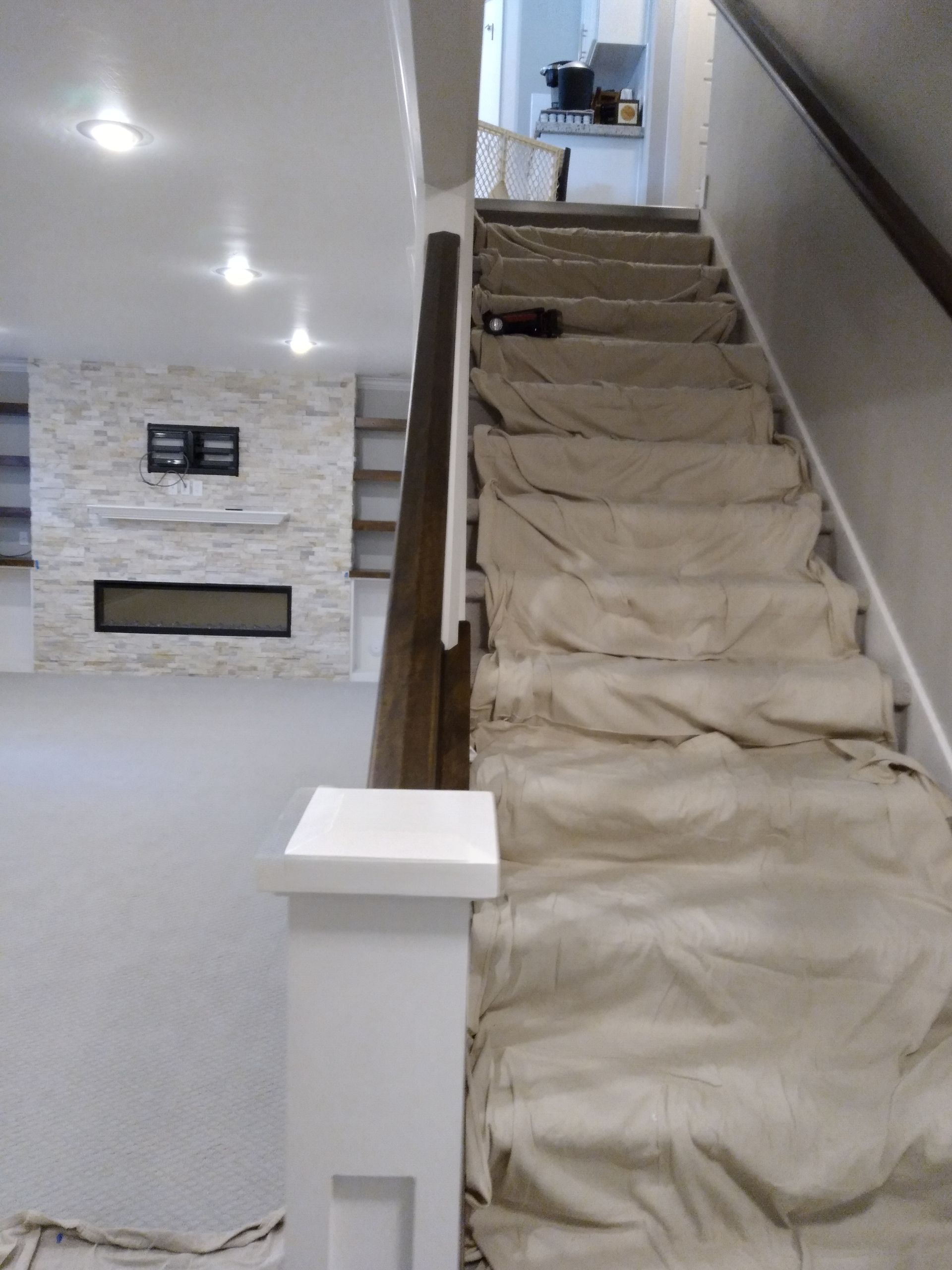 Staircase leading to a kitchen, covered in paper. In the background, a fireplace and bookshelves.