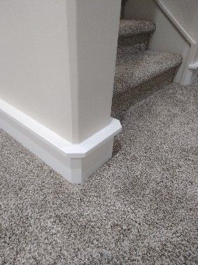 White trim on wall and baseboard meets carpeted stairs.