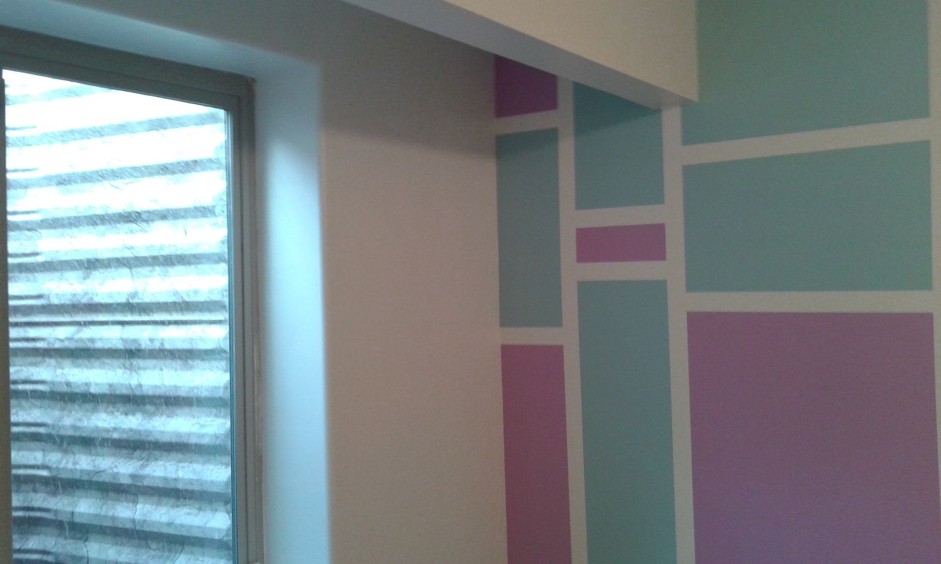 Wall with window, featuring pastel geometric shapes in pink and blue, outlined in white.