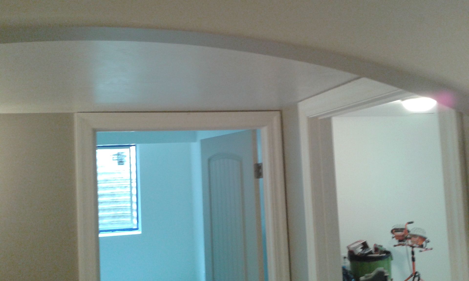 Interior view of an arched doorway leading to another room and a hallway, all with white trim.