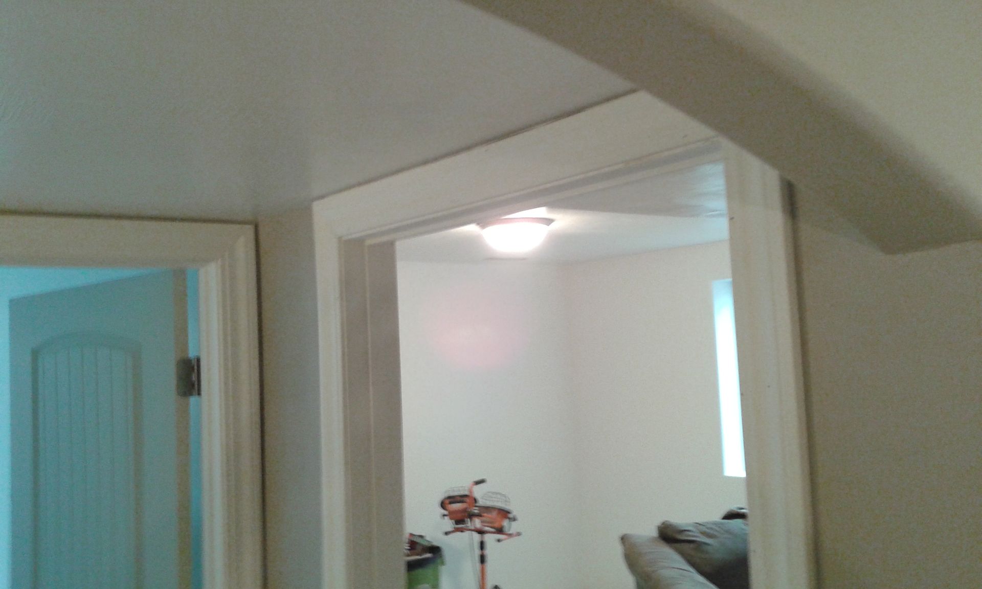 View of a doorway with white trim, leading into a room with a light fixture and window.