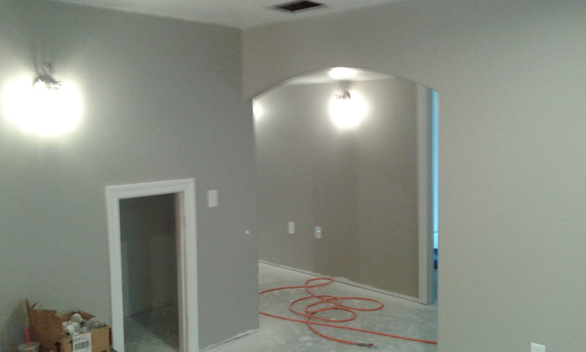 Interior view of room with gray walls, arched doorway, and overhead lights.