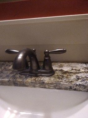 Bathroom faucet with two handles on a granite countertop, above a white sink.