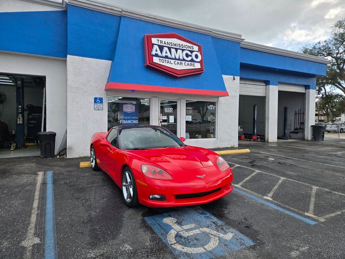 Red sports car parked outside of the AAMCO Sarasota, FL transmission and auto repair shop.