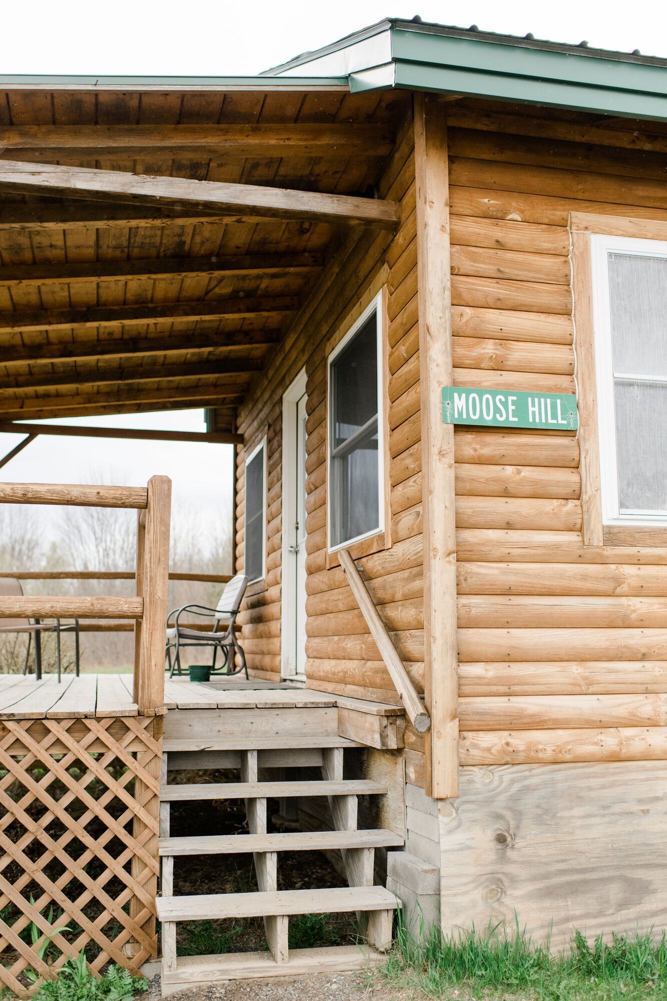 Log cabin porch with steps, lattice, and a green address plaque reading “Knott Hill”