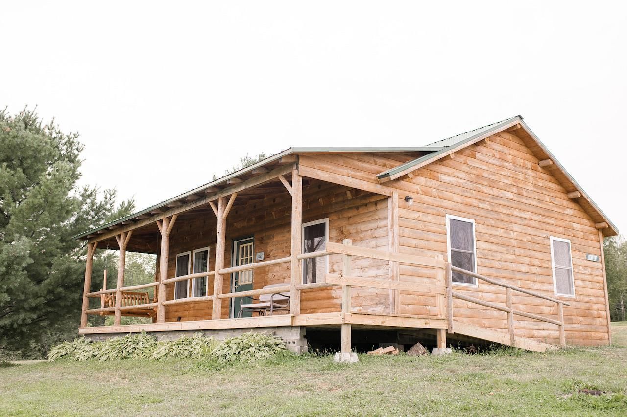 Wooden cabin with a covered porch in a grassy rural setting