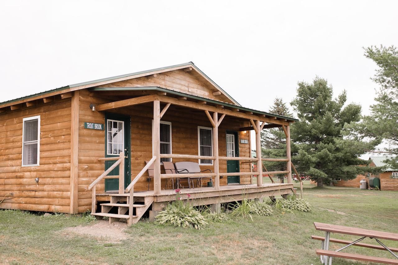 Wooden cabin with a front porch in a grassy rural setting
