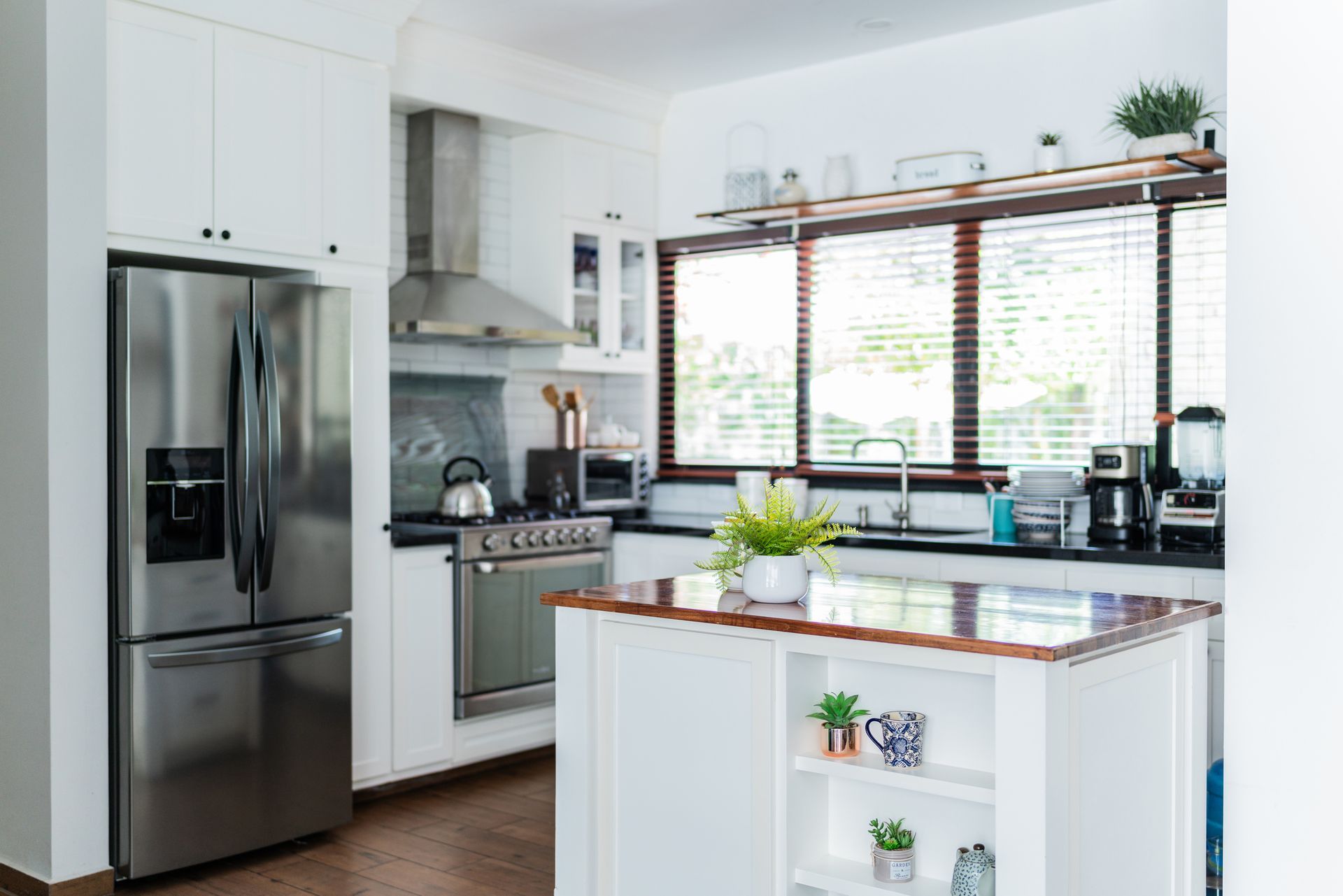 Bright, modern kitchen with white cabinets, stainless steel appliances.