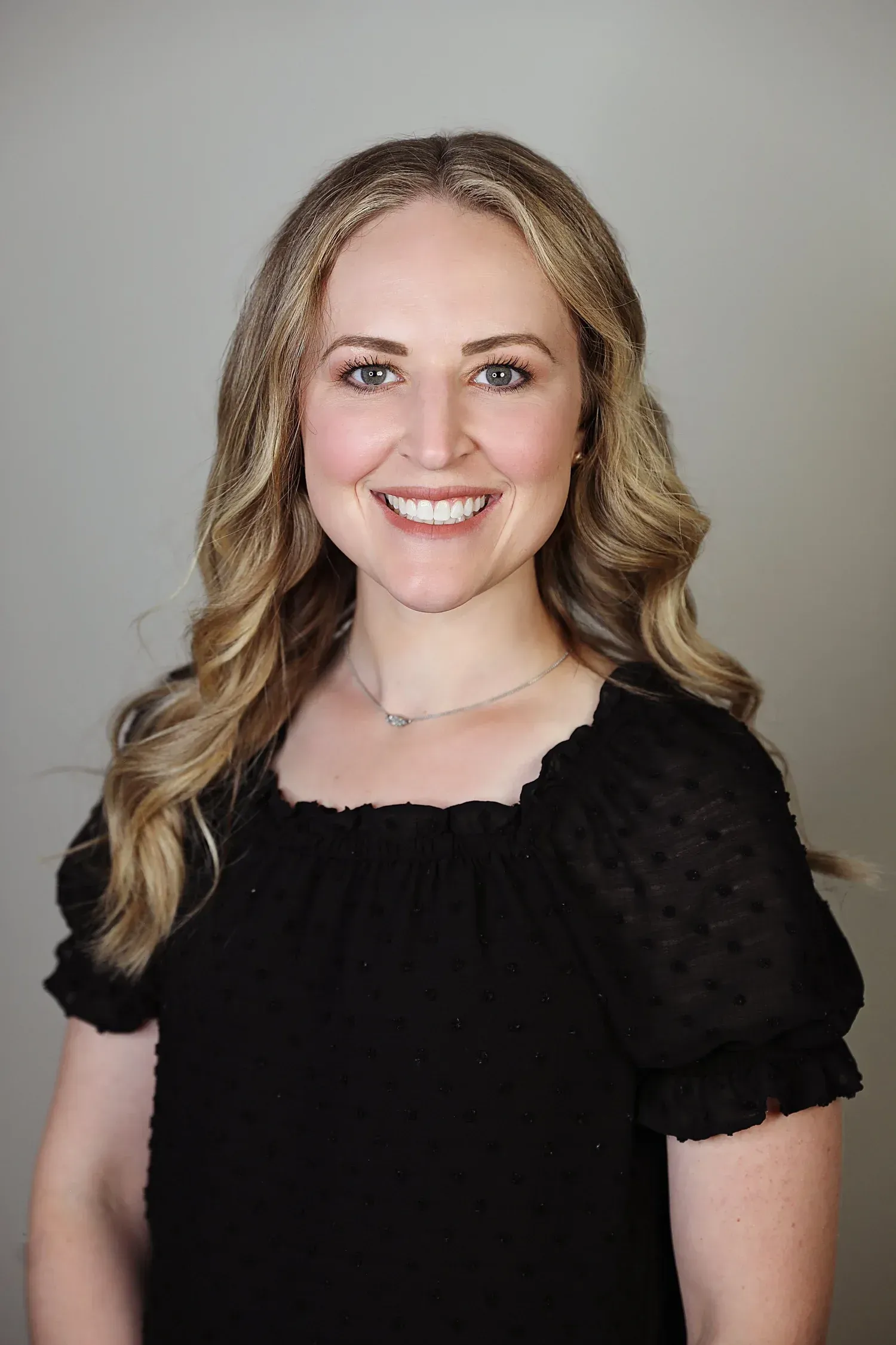 Michelle Hagen, FNP in a blue shirt standing in a bright office-like room
