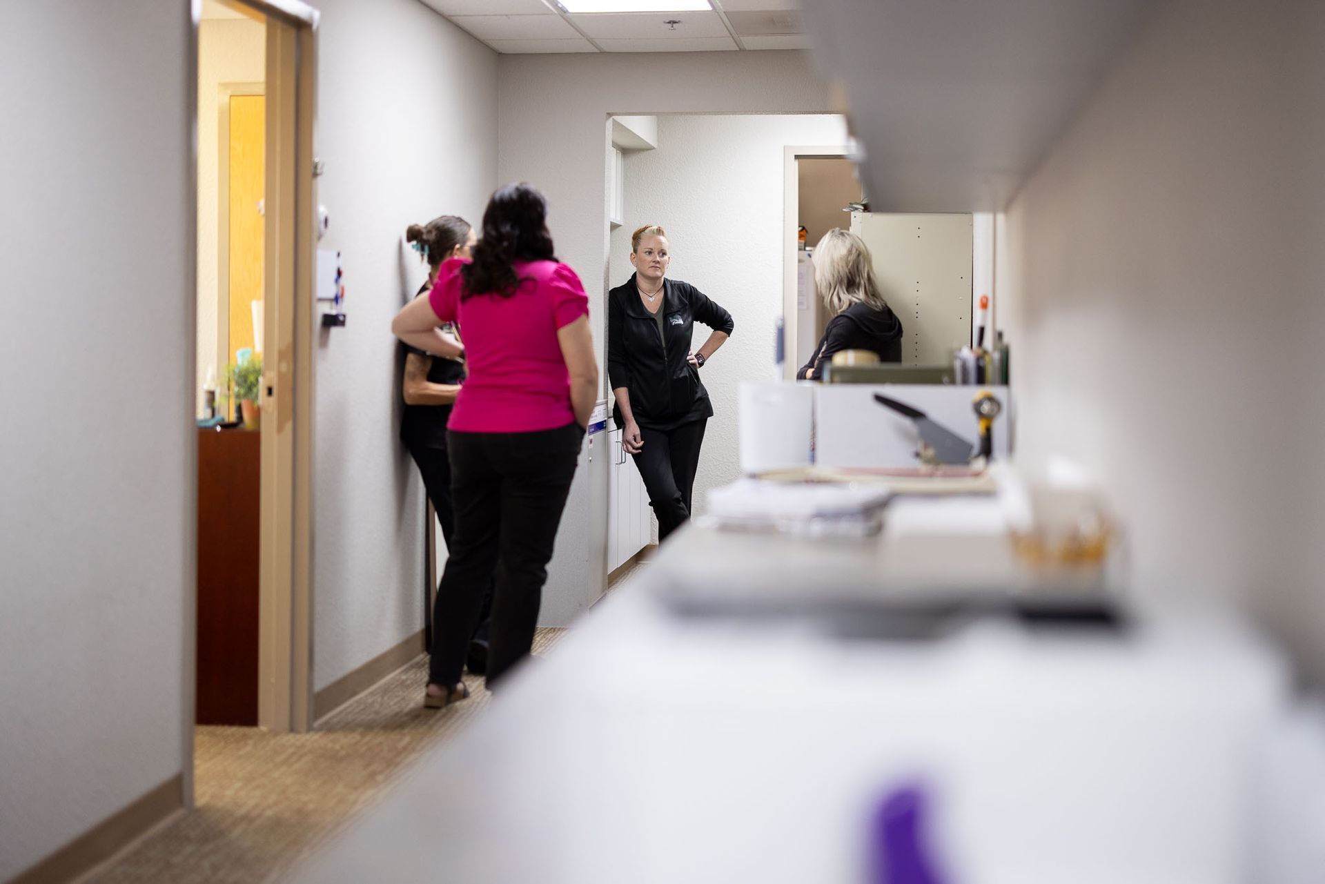 Nurses and doctors standing in a bright hallway near a doorway, with a sink and counter in the foreground.