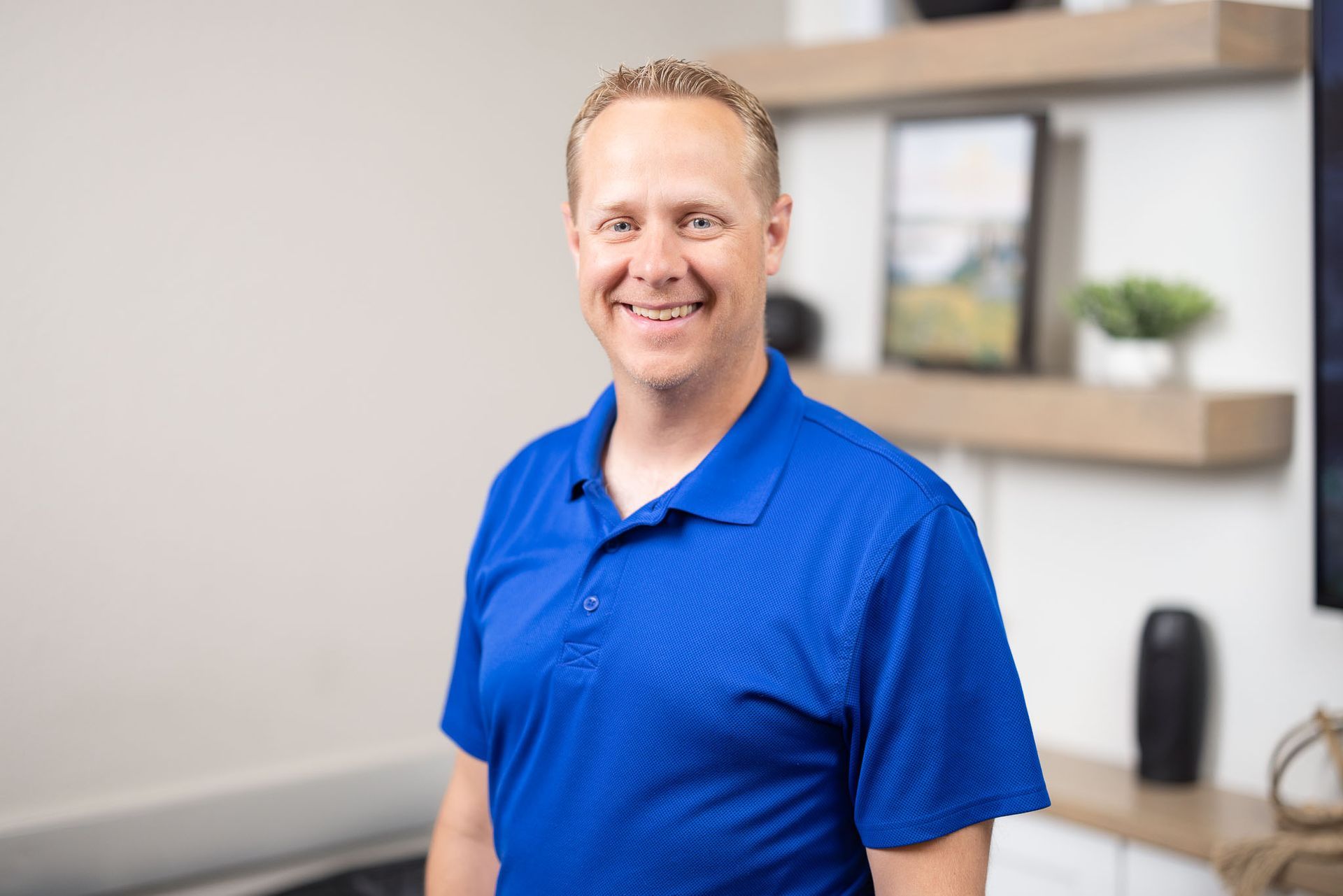 Mark Himes in a blue polo shirt standing in a modern office setting