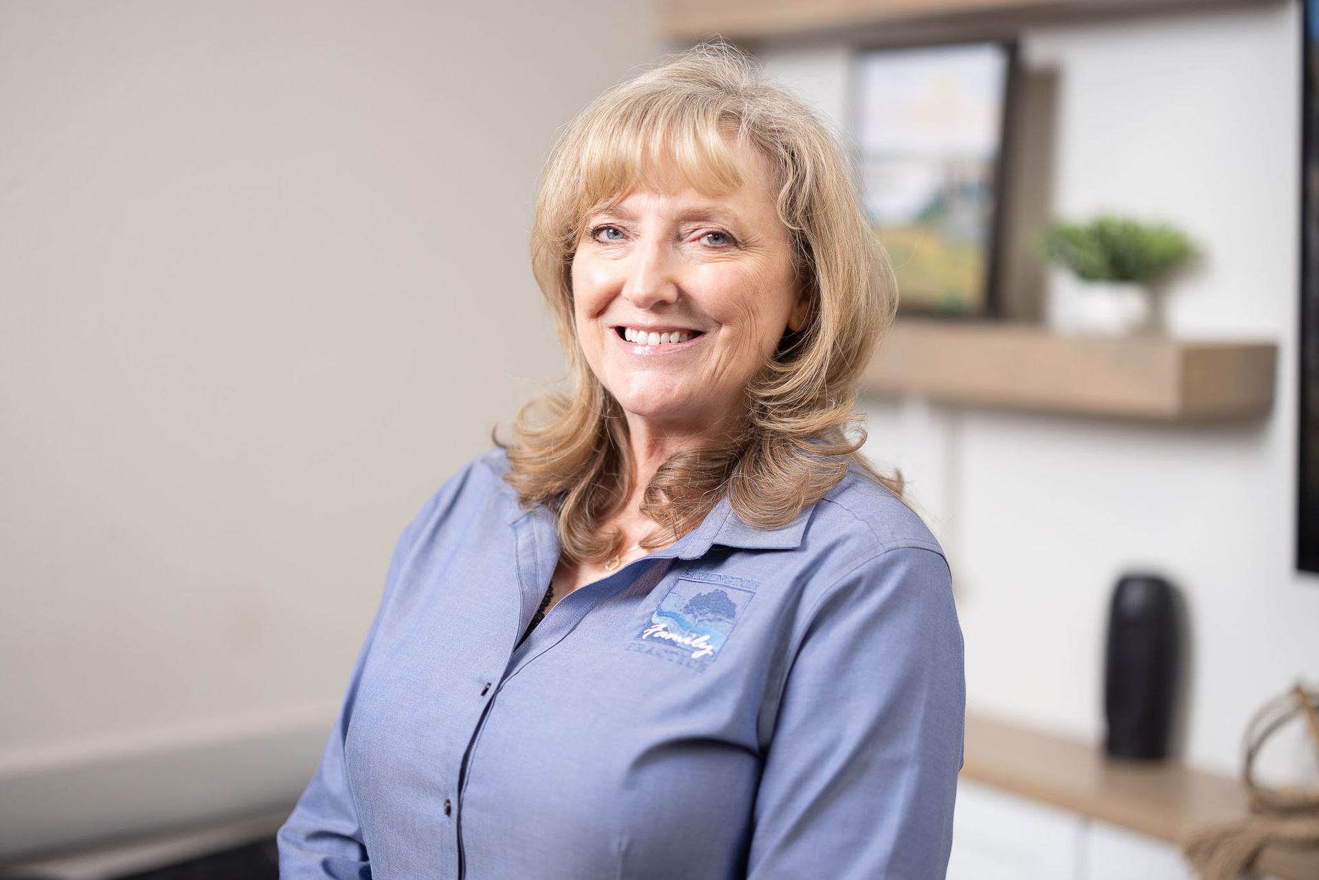 Michelle Hagen, FNP in a blue shirt standing in a bright office-like room