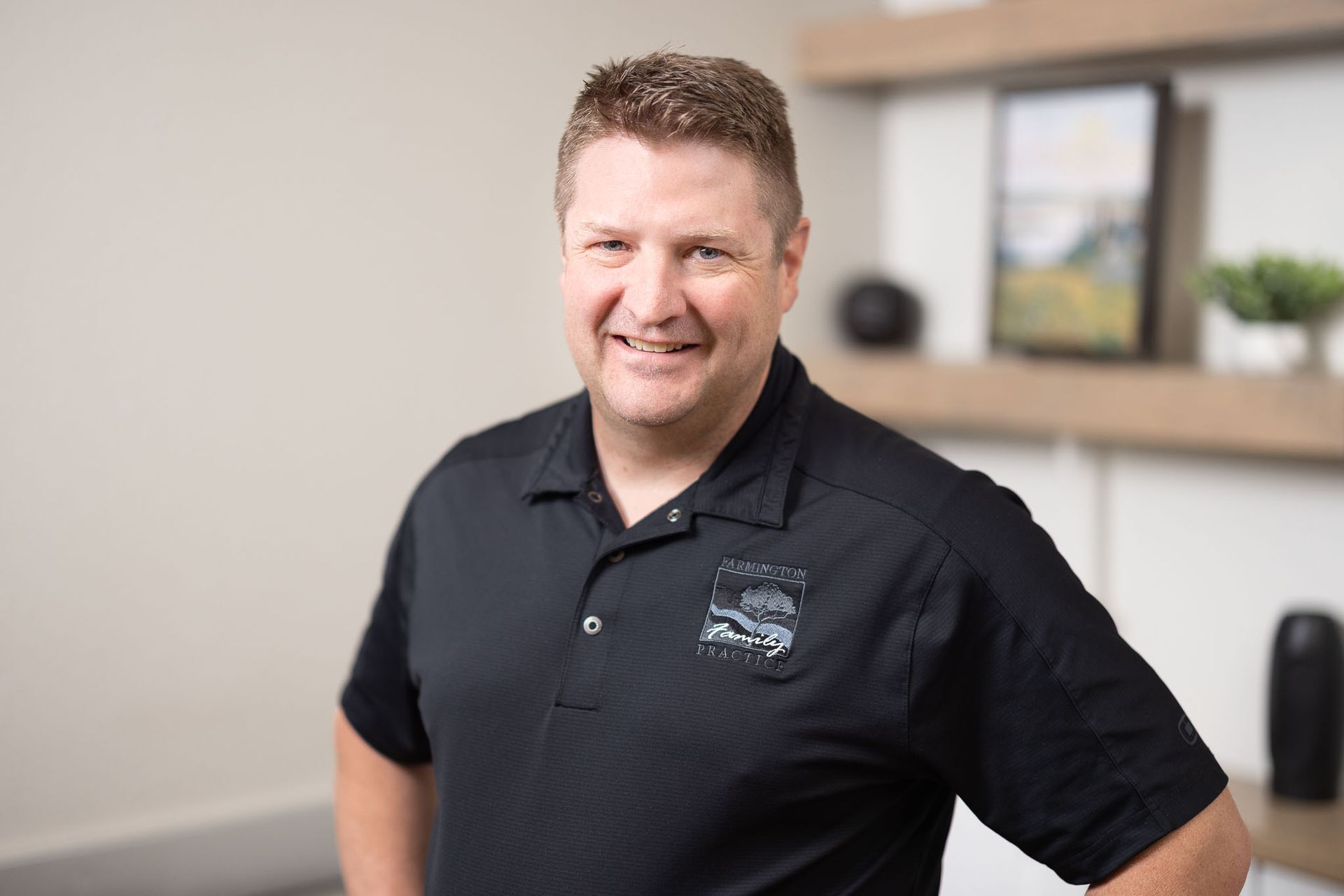 Aaron Rogers, FNP in a black polo shirt standing in an office setting