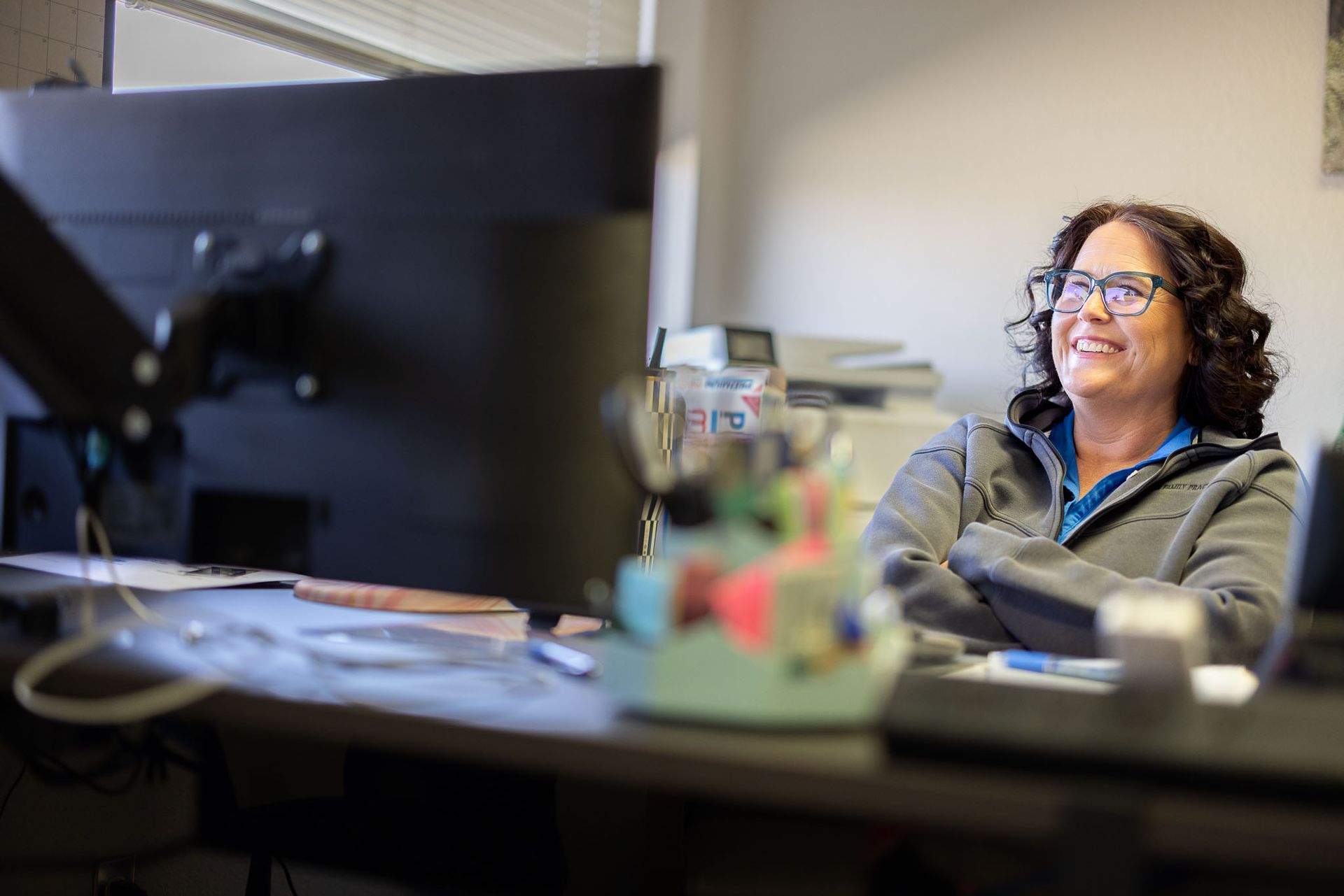 Farmington Family Practice employee smiling at a desk with a large monitor in an office setting