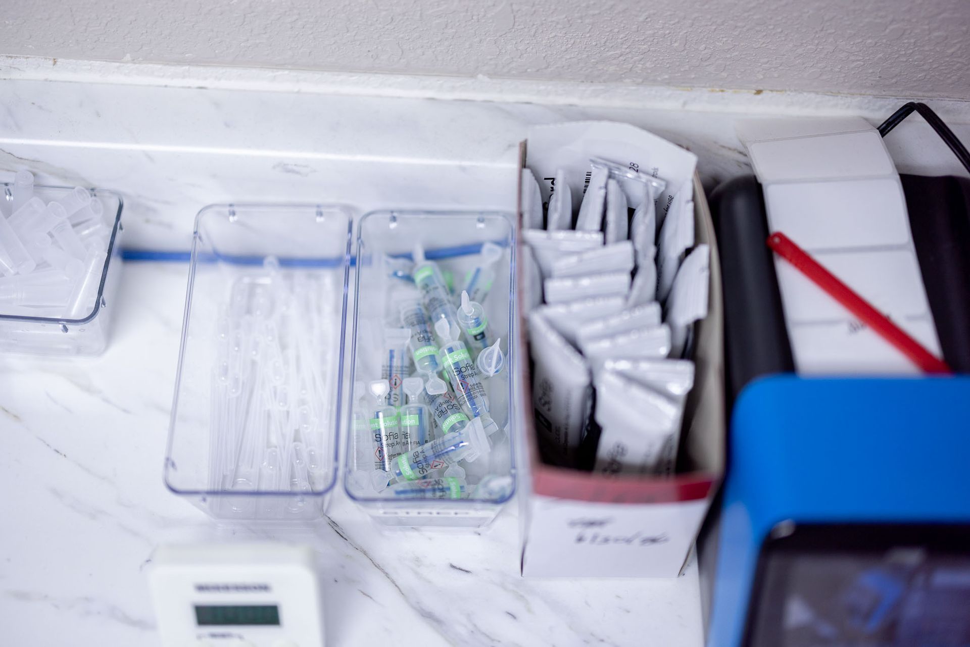 Assorted small items and packets neatly arranged in trays on a white countertop.